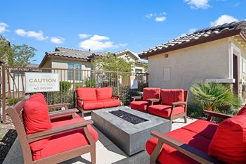 A patio with red chairs and a fire pit